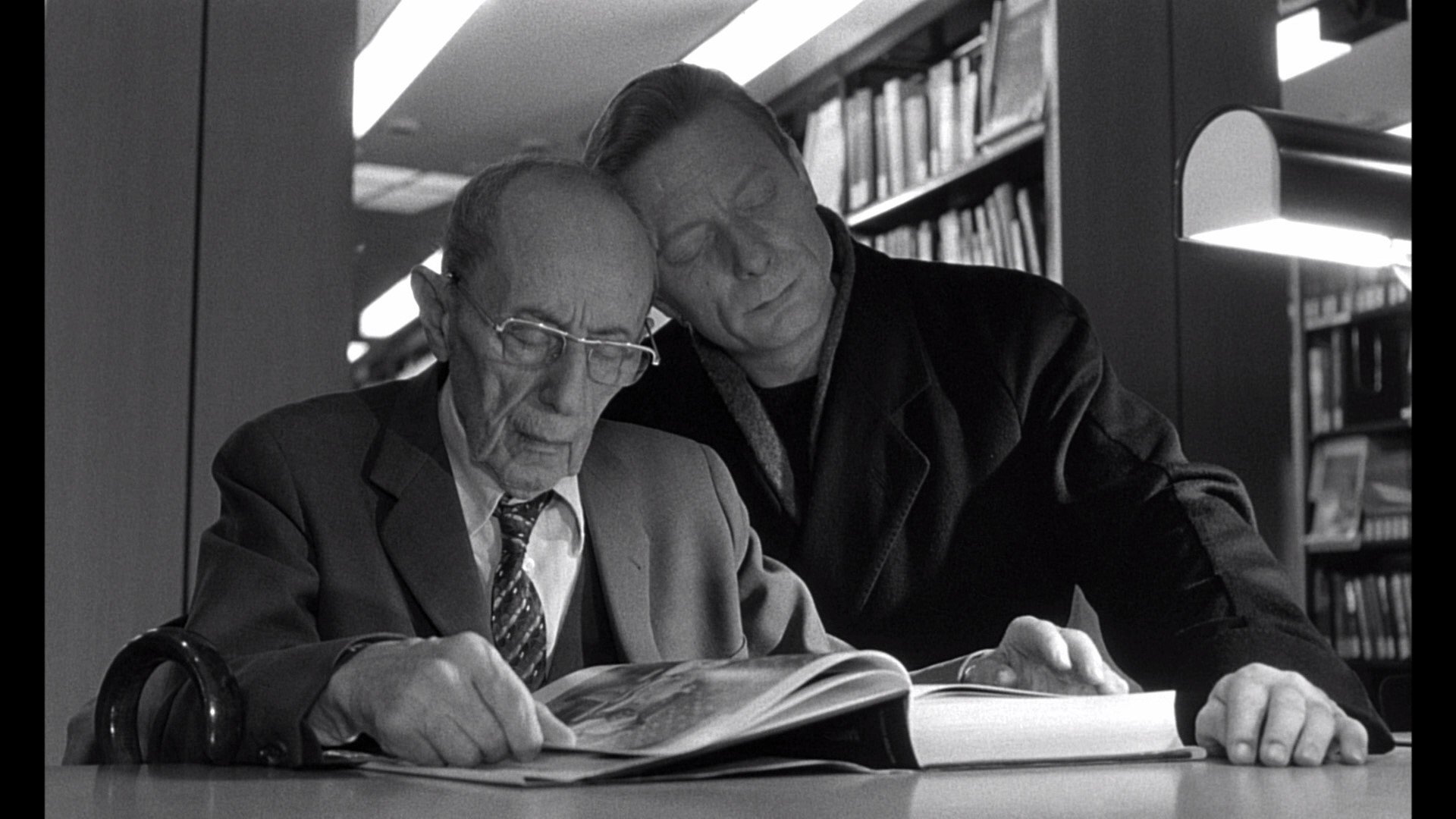 HD wallpaper from Wings of Desire with two characters, one leaning over the other, in a library setting.