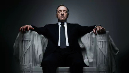HD wallpaper featuring a stern-looking character from House of Cards seated confidently on a throne-like chair.