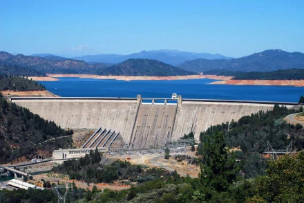 A stunning view of Shasta Dam set against a backdrop of blue waters and mountains, showcasing the impressive human-made structure in a vibrant HD desktop wallpaper.