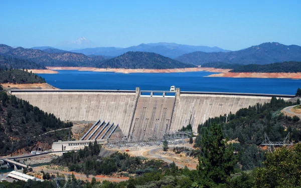 A stunning view of Shasta Dam set against a backdrop of blue waters and mountains, showcasing the impressive human-made structure in a vibrant HD desktop wallpaper.