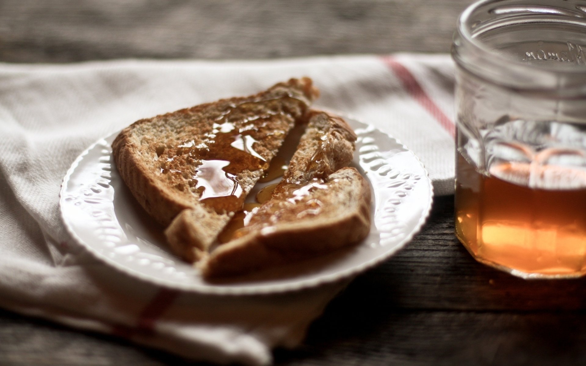 HD food-themed PC wallpaper showing toasted bread drizzled with honey on a plate, accompanied by a glass jar of honey on a rustic wooden table.