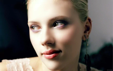HD desktop wallpaper featuring a close-up portrait of a woman with blonde hair and a subtle smile, wearing a light pink outfit and black earrings.
