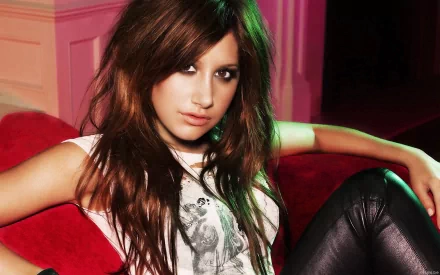 A striking HD desktop wallpaper featuring Ashley Tisdale, showcasing her with long hair and an edgy outfit, exuding confident charm against a vibrant background.