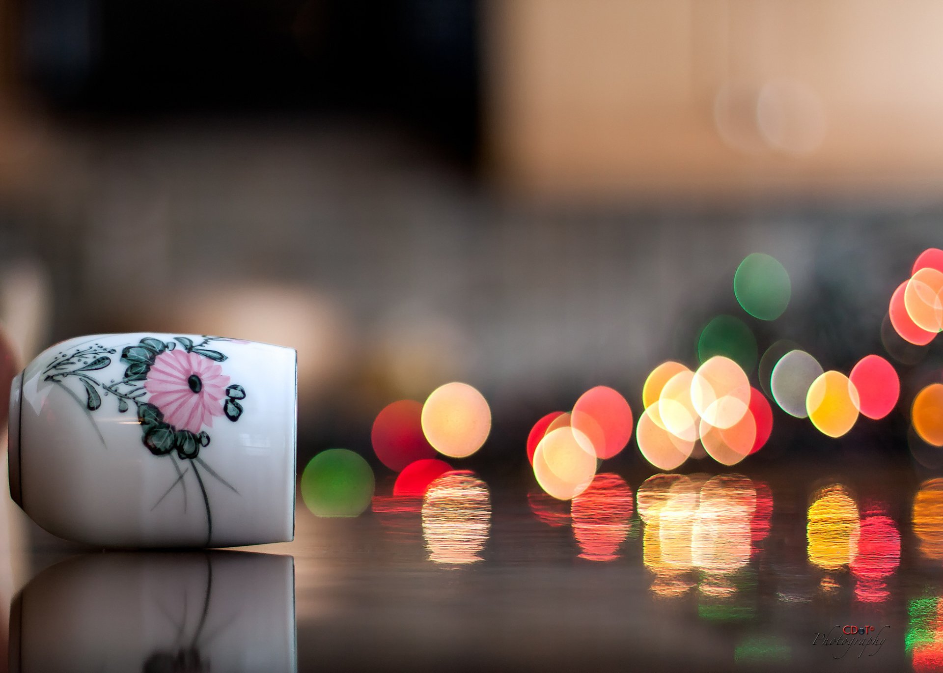Artistic HD desktop wallpaper featuring a delicately painted vase with a floral design, set against a backdrop of vivid, colorful bokeh lights.