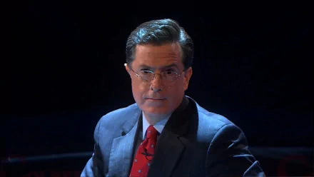 HD wallpaper featuring the host of The Colbert Report in a suit with a red tie, set against a dark background.