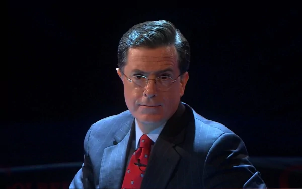 HD wallpaper featuring the host of The Colbert Report in a suit with a red tie, set against a dark background.