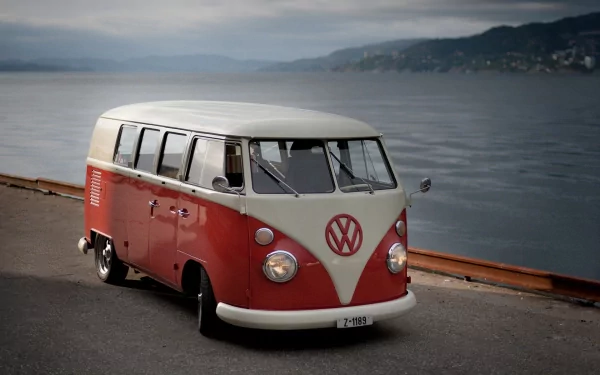 A vibrant Volkswagen van parked by a serene lake, showcasing its classic design against a scenic backdrop, making it a stunning HD PC desktop wallpaper.