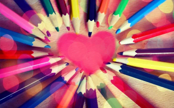 Vibrant HD desktop wallpaper featuring a close-up photograph of colorful pencil tips arranged in a circle around a central pink heart.