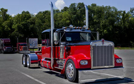 HD desktop wallpaper featuring a red Kenworth truck parked in a lot with trees in the background under a clear sky.