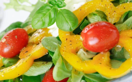 HD PC desktop wallpaper background showing a fresh food salad: cherry tomatoes, yellow bell pepper rings, basil and mixed greens.
