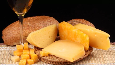 HD PC desktop wallpaper featuring an assortment of cheeses, cheese cubes, and bread against a dark background, highlighting rich textures and warm colors.