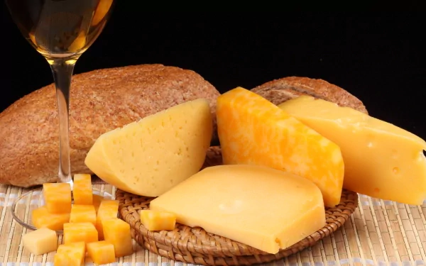 HD PC desktop wallpaper featuring an assortment of cheeses, cheese cubes, and bread against a dark background, highlighting rich textures and warm colors.