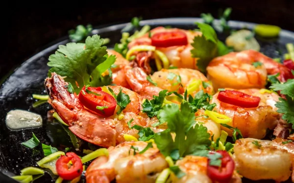 A vibrant HD wallpaper featuring a delicious shrimp dish garnished with fresh herbs, red chilies, and green onions, inviting a feast for the eyes.