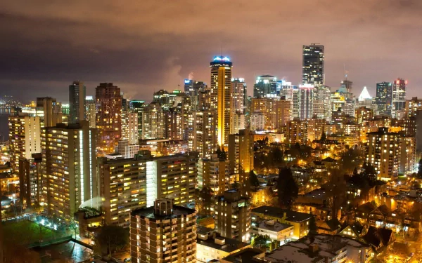 Vibrant night view of Vancouver, Canada, showcasing illuminated skyscrapers and the bustling cityscape, captured in a stunning HD wallpaper.