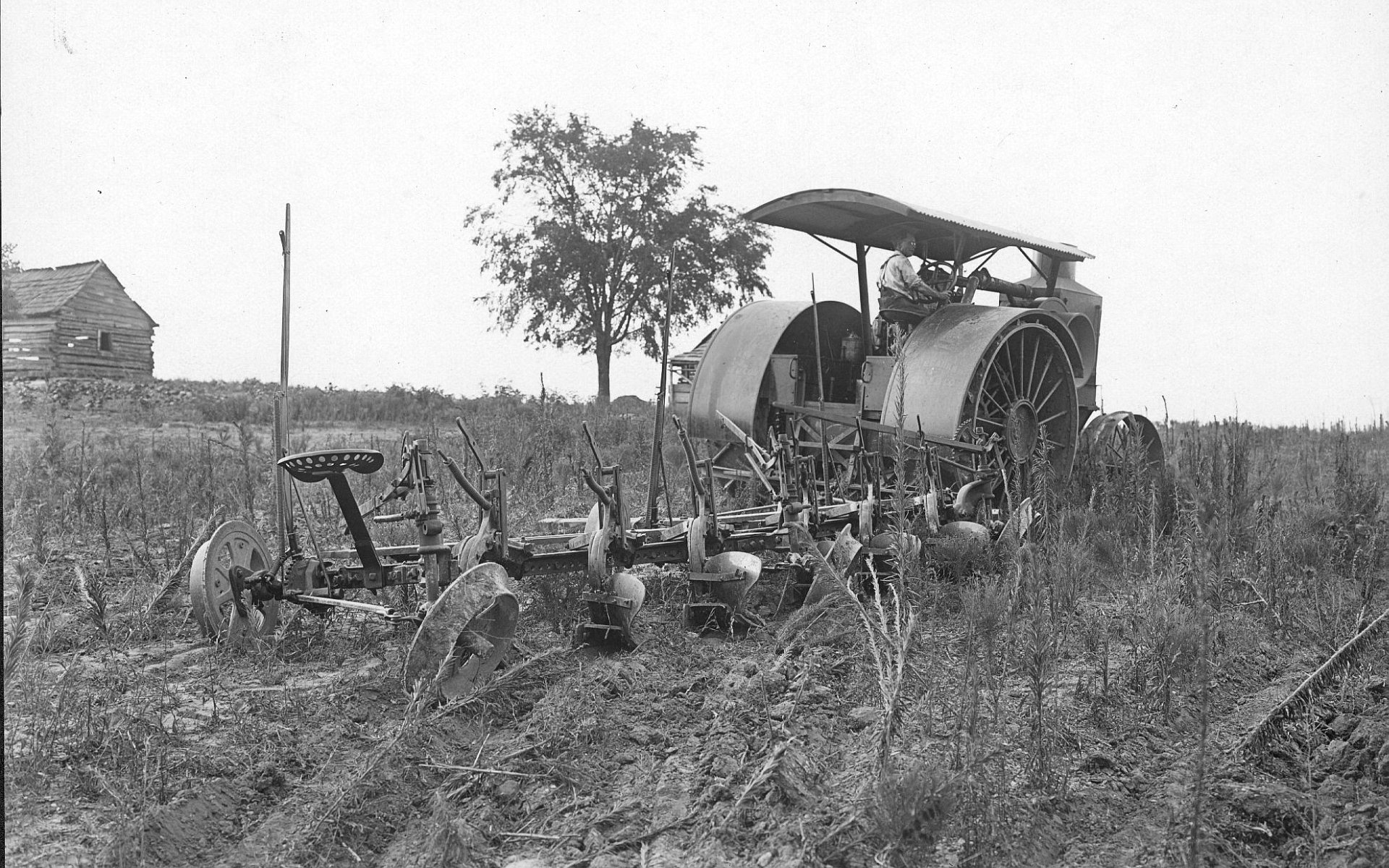 Black and white HD desktop wallpaper showing a vintage tractor with farming equipment in a rural field.