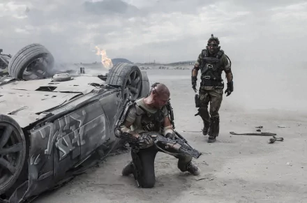 HD wallpaper from the movie Elysium featuring characters in an action scene with a futuristic overturned vehicle and a fiery background.