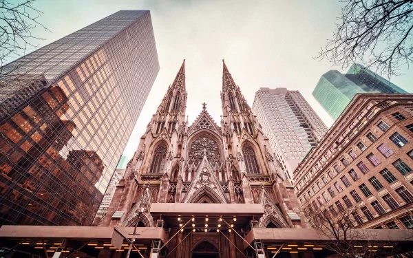 HD desktop wallpaper featuring the towering Gothic spires of St. Patrick's Cathedral framed by modern skyscrapers under a pale sky in a religious urban setting.