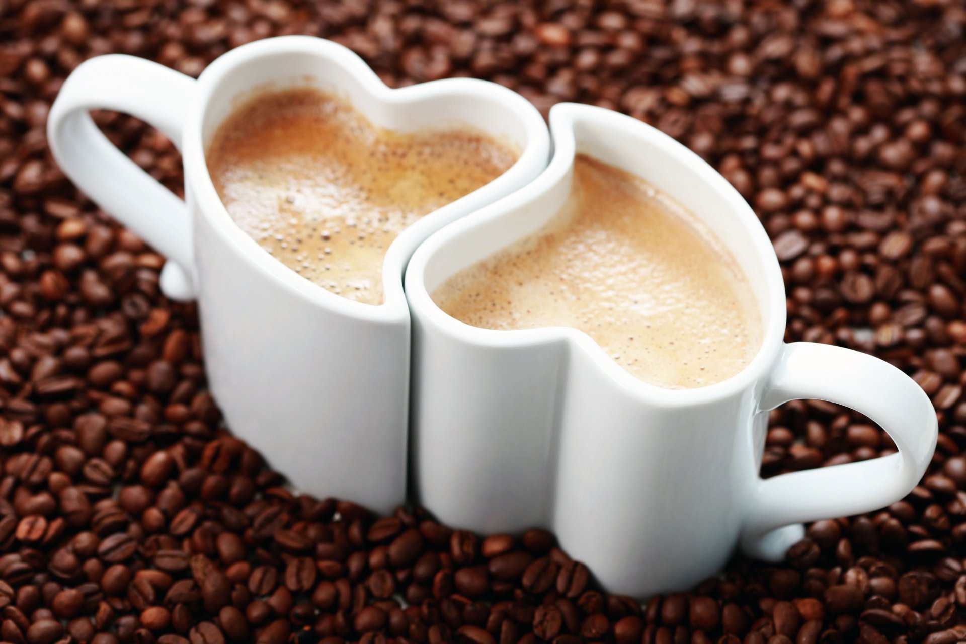 Close-up of two heart-shaped coffee cups filled with coffee, placed together on a bed of coffee beans, presented as a 4K Ultra HD PC desktop wallpaper.