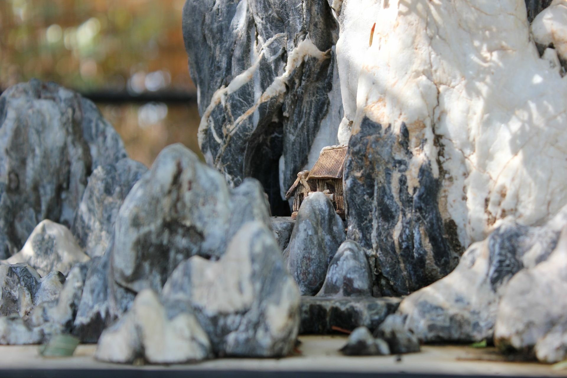 HD desktop wallpaper featuring a close-up of a miniature rocky landscape with a small building nestled among the stones.