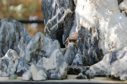 HD desktop wallpaper featuring a close-up of a miniature rocky landscape with a small building nestled among the stones.