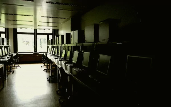 Dim IBM computer lab with rows of monitors and chairs, high-contrast 4K Ultra HD PC desktop wallpaper background showcasing technology.