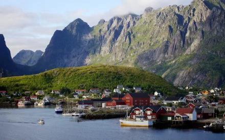 HD PC desktop wallpaper and background photography of Reine, Lofoten, Norway — red rorbuer and boats on a calm harbor beneath dramatic jagged mountains.