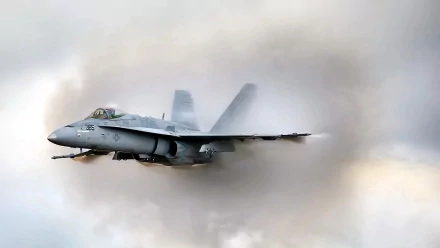 HD desktop wallpaper featuring a McDonnell Douglas F/A-18 Hornet military jet flying through cloudy skies.
