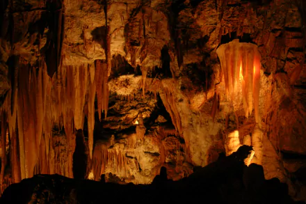 Warmly lit stalactites and stalagmites inside Jenolan Caves, nature cave interior — 2K Quad HD PC desktop wallpaper/background.