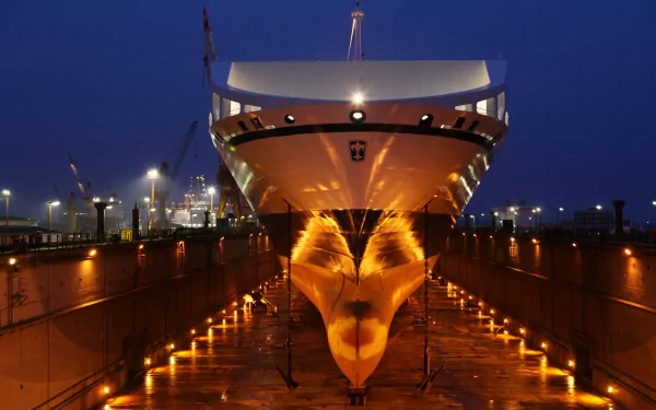 HD desktop wallpaper of a large ship in a man-made shipyard, illuminated at night with reflections on the dry dock floor under deep blue sky.