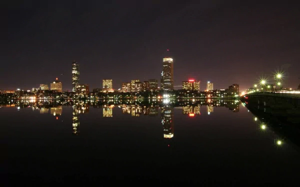 A stunning nighttime view of Boston's skyline, reflecting beautifully on the water. This HD wallpaper showcases the city's man-made architecture and vibrant lights.