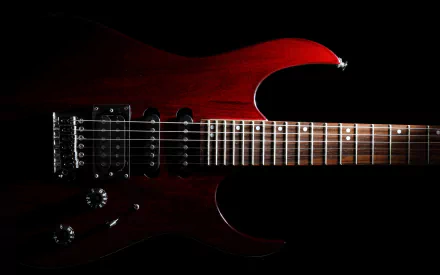 A striking close-up of a rich red guitar against a black background, capturing the essence of music and creativity. This HD wallpaper adds a bold touch to any desktop.