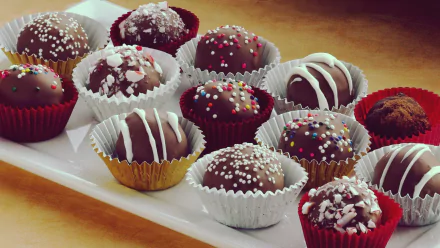 Assorted chocolate truffles, each uniquely decorated and presented on a platter, serve as a vibrant HD desktop wallpaper background.