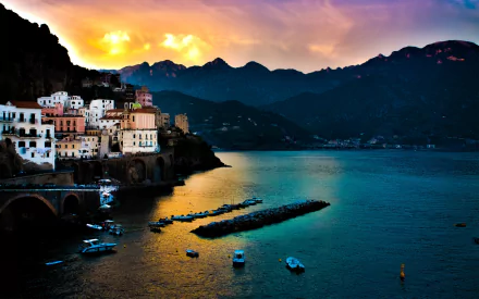 4K Ultra HD wallpaper of Amalfi’s man-made coastal village at sunset, with colorful buildings perched on cliffs overlooking calm waters and boats.
