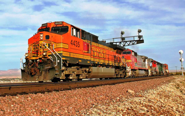 HD desktop wallpaper featuring a vibrant diesel locomotive train traveling on tracks under a partly cloudy sky in a desert landscape.
