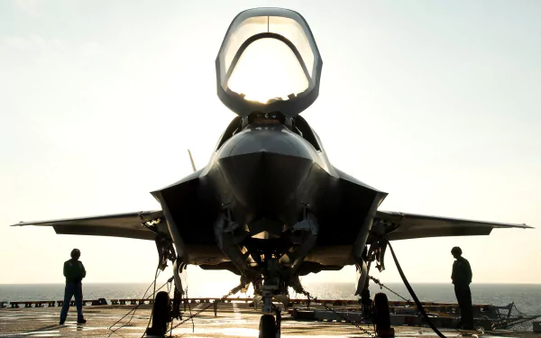 A striking HD wallpaper featuring the Lockheed Martin F-35 Lightning II, showcasing its sleek design against a backdrop of sunlight, with personnel preparing for operations.