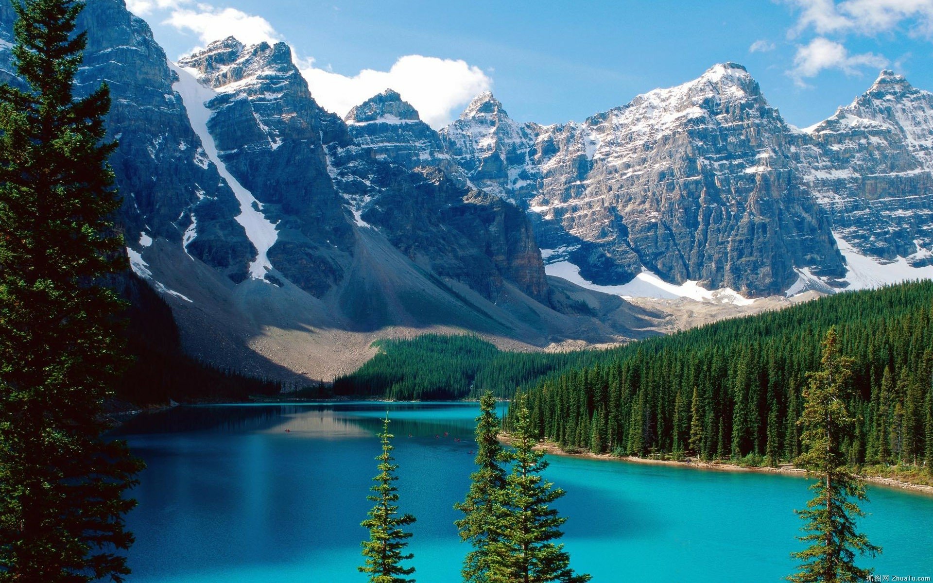 A stunning view of Moraine Lake surrounded by majestic mountains and lush forests. The vibrant blue water reflects the picturesque scenery, creating a serene nature backdrop.