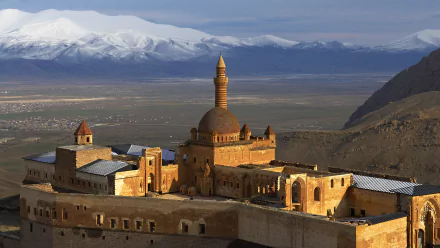 HD desktop wallpaper showcasing the man-made Ishak Pasha Palace with detailed architecture against a backdrop of vast plains and snow-capped mountains.
