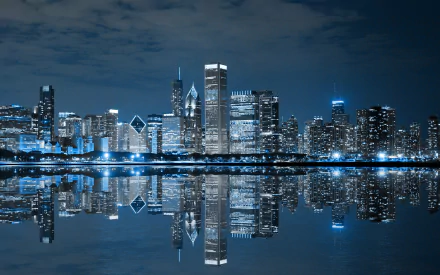 HD wallpaper of the Chicago skyline at night, featuring illuminated skyscrapers and their reflections on a still body of water, creating a stunning, man-made urban landscape.