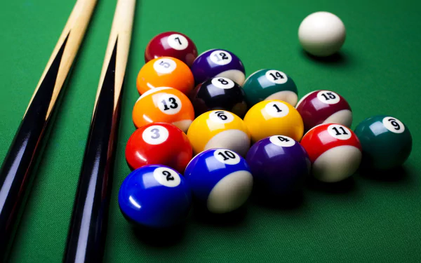 Close-up of a pool table featuring a set of colorful billiard balls arranged for a game, with two pool cues resting beside them, serving as a dynamic HD desktop wallpaper.