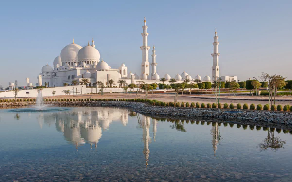 A stunning view of Sheikh Zayed Grand Mosque, featuring its majestic domes and minarets reflected in a tranquil pool, captured in high definition as a captivating desktop wallpaper.