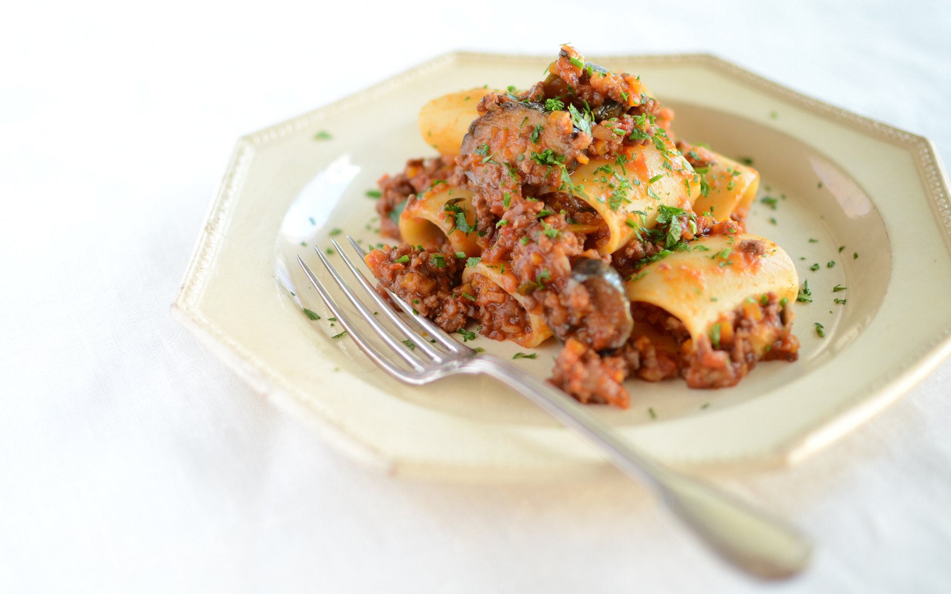 HD PC desktop wallpaper and background, food breakfast close-up: pasta rolls topped with hearty meat sauce and parsley on a cream plate with a fork.