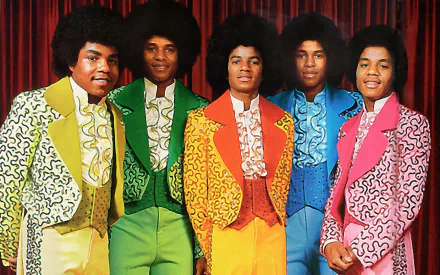 HD desktop wallpaper featuring The Jackson 5 dressed in vibrant, colorful suits standing against a red curtain, celebrating iconic music history.