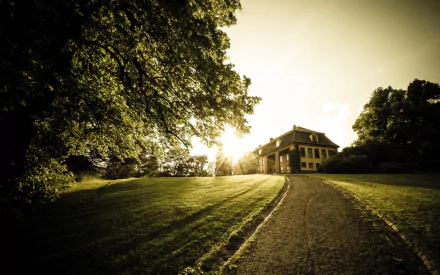 A scenic HD desktop wallpaper featuring a grand house bathed in warm sunlight, set against lush greenery and a winding pathway leading up to the entrance.