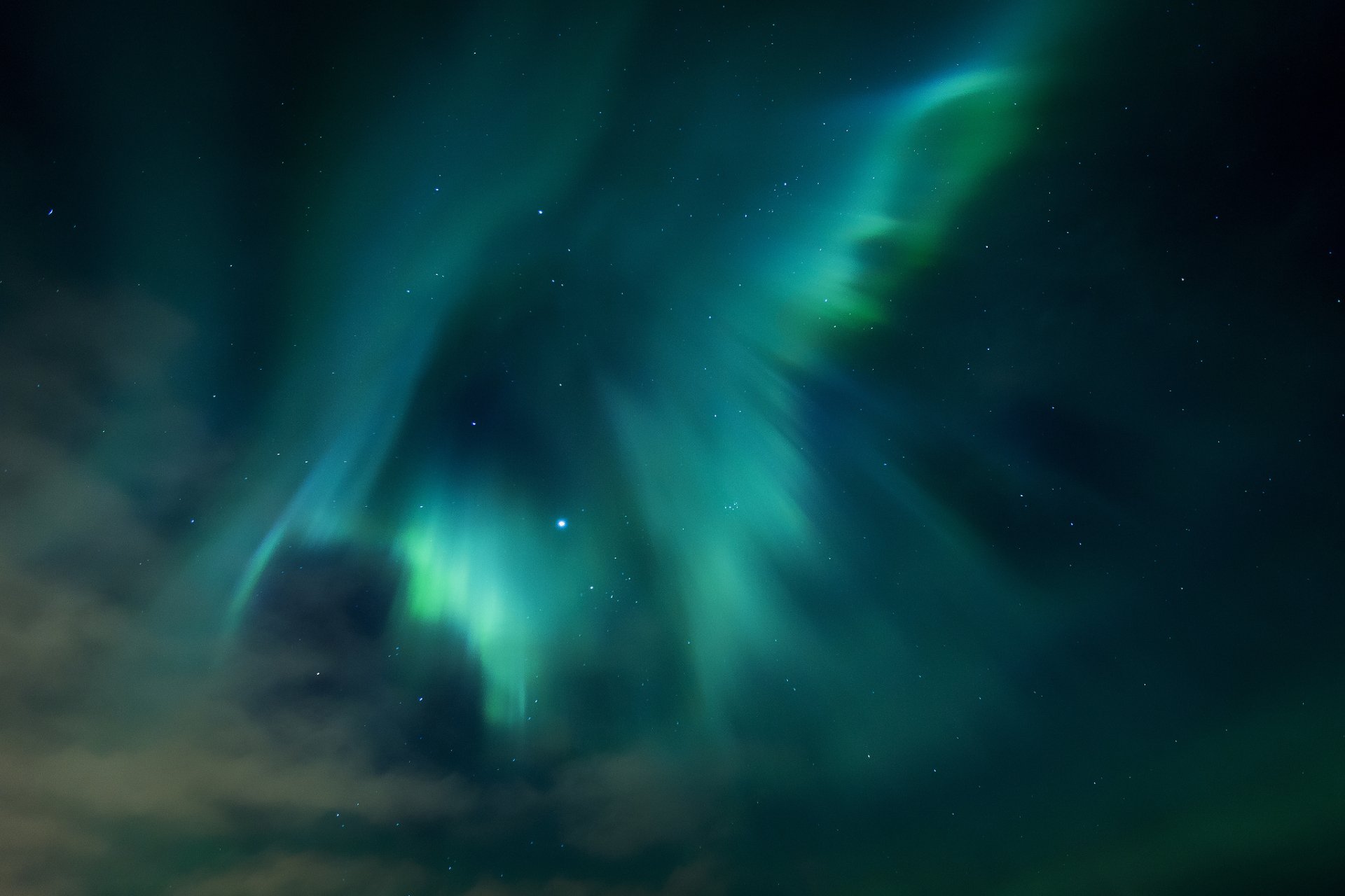 HD desktop wallpaper showcasing vibrant green and blue aurora borealis lights dancing across a dark night sky over a serene nature landscape.