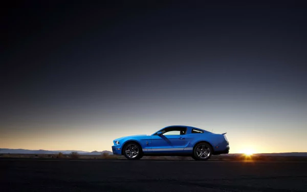 Blue Ford Mustang Shelby Cobra GT 500 in profile on an open road at sunset, HD PC desktop wallpaper background.