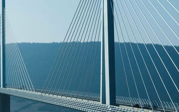 HD desktop wallpaper featuring the Millau Viaduct, a striking man-made cable-stayed bridge set against a clear sky and distant hills.