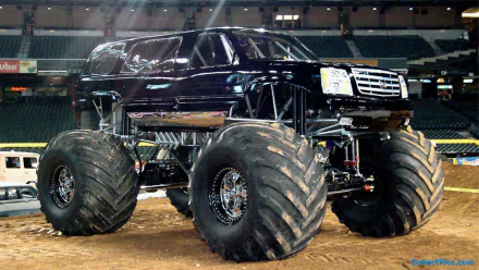 A striking black monster truck with oversized tires, showcased in an arena setting, serves as a bold HD PC desktop wallpaper and background.