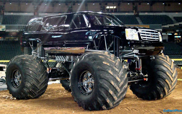 A striking black monster truck with oversized tires, showcased in an arena setting, serves as a bold HD PC desktop wallpaper and background.