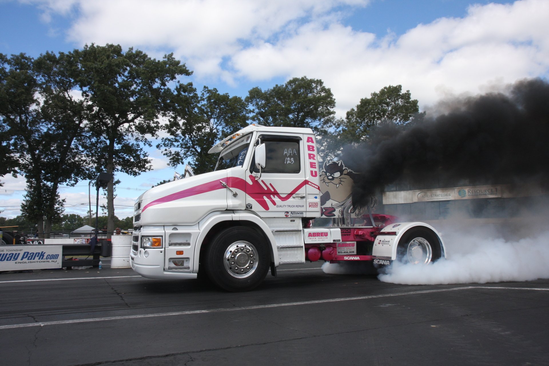 4K Ultra HD PC desktop wallpaper of a white and pink Scania truck emitting thick black smoke, set against a backdrop of trees and a partly cloudy sky.