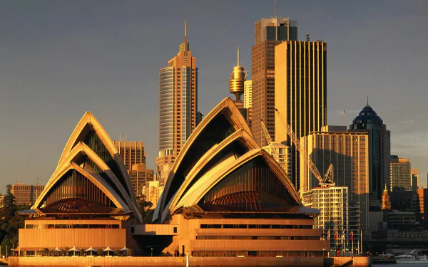 HD desktop wallpaper showcasing the Sydney Opera House with city skyscrapers in the background, highlighting iconic man-made architecture in Sydney at golden hour.
